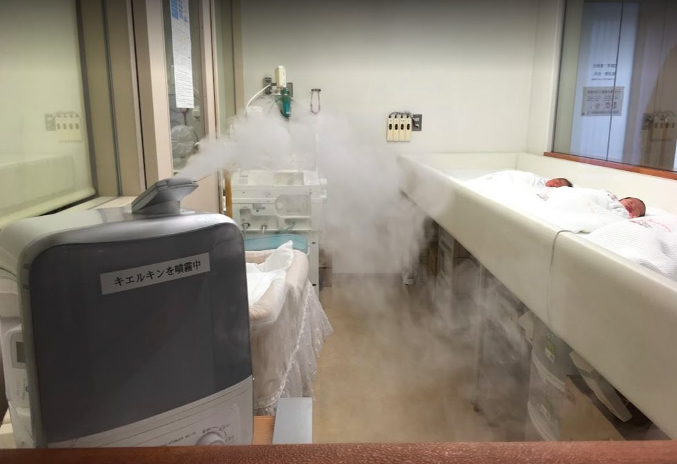 新生児室でキエルキンを噴霧している装置。「キエルキンを噴霧中」のラベルが貼られ、奥には新生児のベッドが並ぶ。